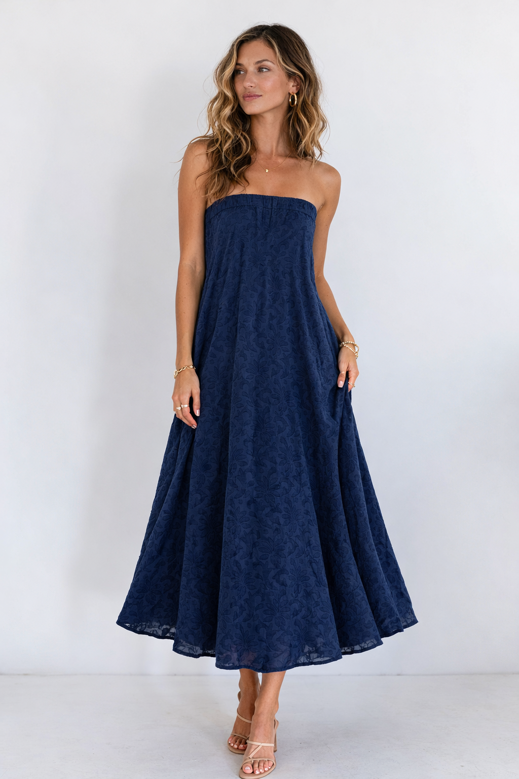 Woman wearing a navy strapless dress against a white background